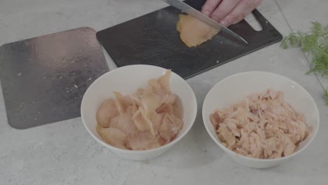 Slow-Motion-Shot-Of-An-Individual-Cutting-Meat-Up-Into-Smaller-Pieces-And-The-Transferring-Them-Into-A-Smaller-Bowl