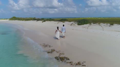 COUPLE-WALKING-ON-sand-beach-hands-to-hands
