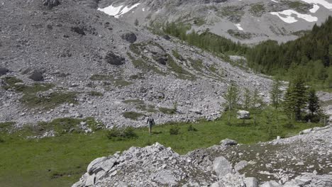 Hiker-walking-down-valley-grass,-Rockies,-Kananaskis,-Alberta-Canada