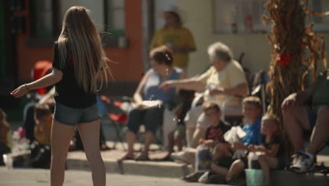 Fit-young-girl-in-shorts-tossing-free-candy-to-children-along-parade-route,-Slow-Motion