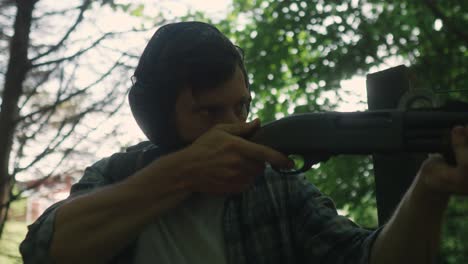 young-caucasian-with-earmuffs-shooting-in-the-forest-with-shotgun-weapon