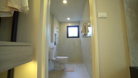 Small-Restroom-With-Light-Beige-Ceramic-Tile-With-Walk-In-Closet-in-Foreground,-No-People,-Approach-Shot