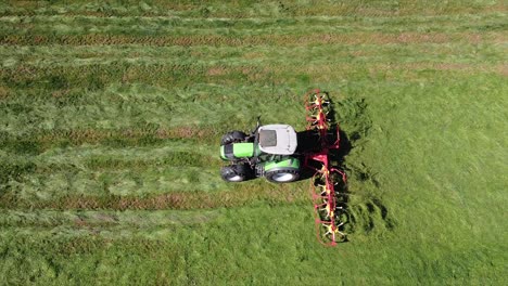 Aerial-Tractor,-agricultural-machine-making-hay,-driving-over-field,-top-down-shot