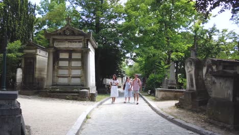 Shot-Of-3-Tourists-Walking-Towards-the-Camera-in-one-of-The-Alley-of-Père-Lachaise-Cemetery,-Paris-France