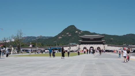 People-tourists-walking-and-sightseeing-in-front-of-Gwanghwamun-gate-and-Bugaksan-mountain-on-clear-sky-day---Wide-angle-static