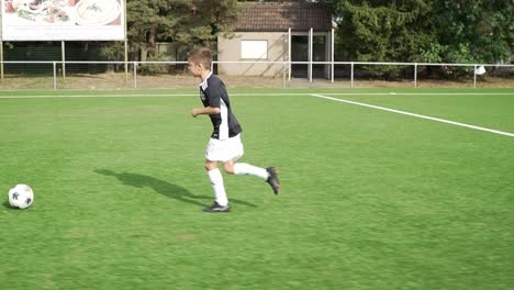 Junger-Fußballspieler,-Der-Seine-Fußballbewegungen-Zeigt-Und-Den-Ball-Ins-Tor-Tritt