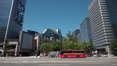 Red-Seoul-city-tour-bus-parked-waiting-for-tourists-at-downtown-Sejong-daero-street-surrounded-with-high-rise-office-buildings-of-modern-architecture---establishing-shot