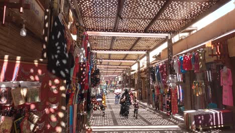 Madre-Caminando-Con-Su-Hijo-A-Lo-Largo-De-Las-Tiendas-Tradicionales-Del-Mercado-En-Luxor-Debajo-De-La-Sombrilla