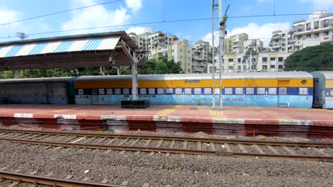 Leerer-Indischer-Bahnhof-Mit-Einigen-Passagieren-Und-Zug-In-Der-Nähe-Einer-Kleinen-Stadt-In-Indien-|-Leerer-Bahnhofsbahnsteig-In-Indien,-Gleise,-Güterzug-Und-Bahnsteig