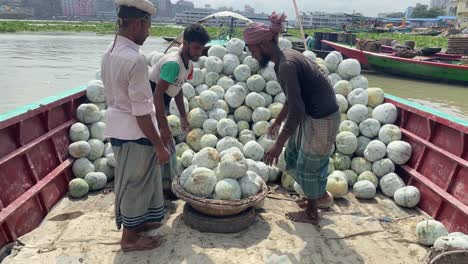Daily-laborer-loading-and-carrying-Ash-Gourd-vegetables-from-boat-at-Buriganga-River-in-Dhaka,-Bangladesh