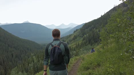 Hikers-walking-downhill-on-a-trail-in-high-altitude-followed-Rockies-Kananaskis-Alberta-Canada