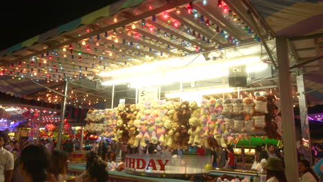 Lights-flash-as-a-diverse-crowd-of-people-walk-around-a-carnival-at-night