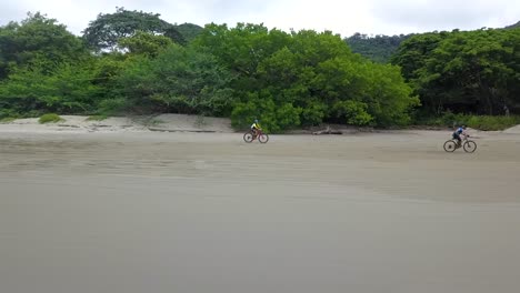 drone-aerial-video-in-nicaragua-beach,-san-juan-del-sur,-palm-,-managua,-rivas,-bicyclist-on-the-beach,-matagalpa