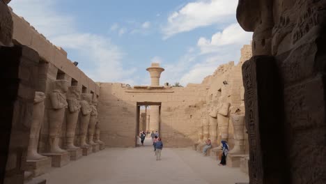 Turistas-Caminando-En-Una-Sala-Al-Aire-Libre-Llena-De-Esculturas-De-Arenisca-En-El-Templo-De-Karnak
