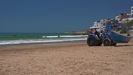 Tractor-carrying-a-small-fisherman-boat-on-the-beach-in-Taghazout