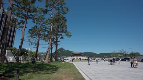 Touristen,-Die-Am-Seoul-Gwanghwamun-Plaza-Besichtigen,-Mit-Weitem-Blick-Auf-Touristen,-Die-An-Einem-Sonnigen-Tag-Zum-Gwanghwamun-tor-Gehen---Statische-Weite-Landschaft