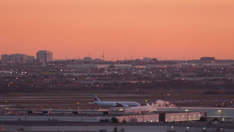 Orangefarbener-Sonnenuntergang-über-Dem-Weißen-Rauch-Des-Flughafens,-Der-Die-Landebahnkabine-Kanadischer-Flugzeuge-Aufbläst