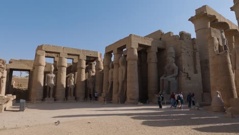 Tourists-visiting-the-ruins-of-Luxor-Temple-in-Egypt,-majestic-pillars-and-statues