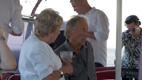 Older-couple-talk-to-each-other-on-a-sail-boat-wedding-party