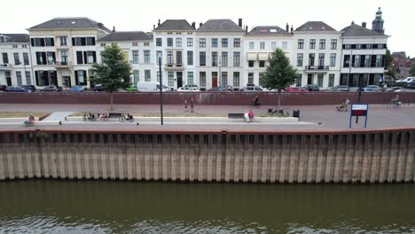 Sideways-aerial-movement-showing-people-doing-recreational-activities-on-the-IJsselkade-boulevard-of-tower-town-Zutphen-showing-low-water-level-of-river-IJssel-in-the-foreground