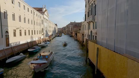 Boot,-Das-Touristen-Transportiert,-Gefolgt-Von-Einem-Kleineren,-Das-An-Einem-Sommerabend-Auf-Einem-Kanal-In-Venedig-Vorbeifährt