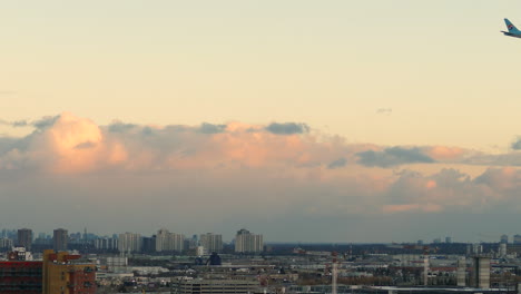Korean-Air-Boeing-777-Airplane-Flying-Above-Cityscape-Skyline-of-Toronto,-Canada-at-Sunset
