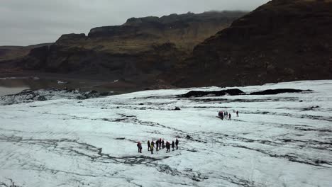 Aerial-view-over-people-hiking-on-Sólheimajökull-glacier,-Iceland,-in-summer