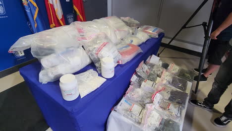 A-dolly-shot-of-a-table-displaying-illegal-drugs-and-narcotics-seized-as-evidence-from-a-drug-bust-by-Peel-Regional-Police-after-investigating-a-syndicate-operating-in-Mississauga-area,-Canada