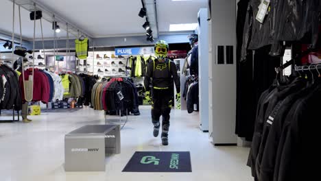 Man-walking-towards-the-camera-and-changing-outfits-in-a-biker-shop