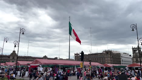 Zeitlupenaufnahme-Der-Mexikanischen-Flagge,-Die-Mit-Voller-Sicht-Auf-Den-Zocalo-Im-Hintergrund-Weht
