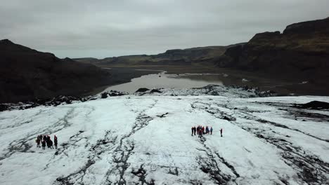 Aerial-landscape-view-of-people-hiking-on-Sólheimajökull-glacier,-Iceland,-in-summer