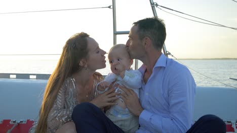 Happy-travelling-family-on-a-sail-boat-kissing-their-baby-boy-on-the-forehead