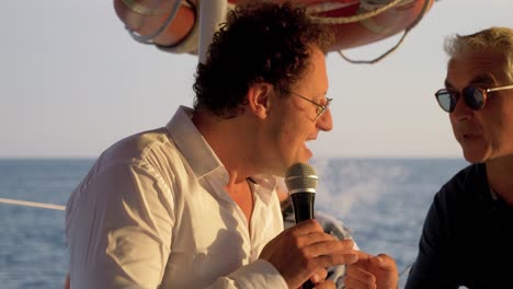 Man-giving-a-speech-through-a-microphone-on-a-catamaran-sail-boat
