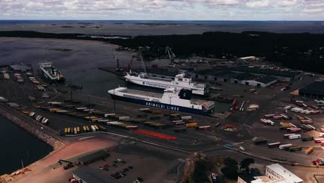 Aerial-view-of-ferries-at-a-shipping-harbor,-sunny,-summer-day-in-Hanko,-Finland---pull-back,-drone-shot