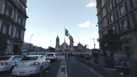 Road-to-Metropolitan-Cathedral-Mexico-City-CDMX-Cars-Passing-by-Central-Avenue-Historic-Location-Latin-American-Capital-National-Flag-Waving