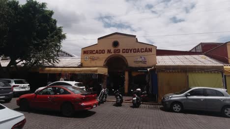 Fassade,-Eingang-Zum-Traditionellen-Lokalen-Coyoacan-markt,-Straßen-Von-Cdmx-autos,-Die-An-Einem-Sonnigen-Tag-An-Mexiko-stadt-Vorbeifahren