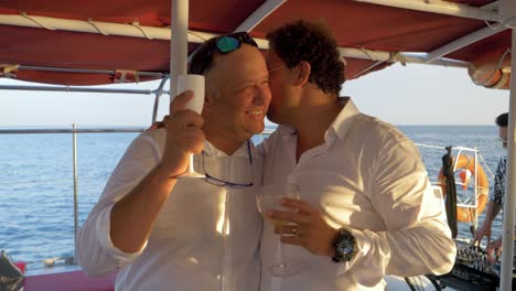 Happy-guys-cheers-and-talk-on-a-catamaran-wedding-party
