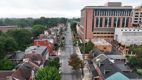 Aerial-tracking-shot-of-quaint,-small-city-street-lined-with-townhomes-and-trees