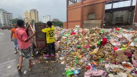 Locals-Beside-Municipal-Waste-Building-Beside-Pile-Of-Garbage-On-Road-In-Bangladesh