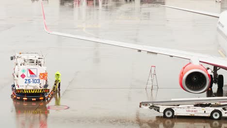 An-employee-of-the-ground-service-of-the-airport-operating-the-tanker-refills-the-aircraft-with-aviation-fuel-on-rainy-days-in-Bangkok
