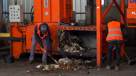 Workers-throw-garbage-into-a-waste-compactor