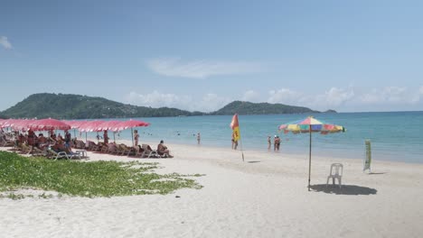 Weißer-Sandstrand-Mit-Grünblauem-Farbmeer-In-Der-Sommerferienzeit-In-Phuket,-Thailand,-Die-Menschen-Entspannen-Sich-Am-Strand