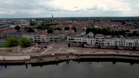 Sideways-aerial-movement-showing-IJsselkade-boulevard-of-tower-town-Zutphen-under-construction-with-low-water-level-of-river-IJssel-in-the-foreground
