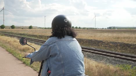 Mujer-Con-Chaqueta-De-Jeans-Conduciendo-Lentamente-En-Una-Bicicleta-Con-Un-Scooter-Eléctrico