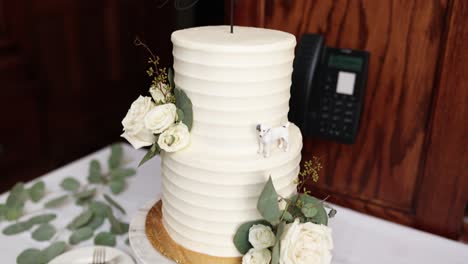 White-wedding-cake-decorated-with-flowers-and-a-small-dog-figurine