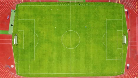 Top-Down-Shot-Flying-Away-From-a-Colorful-Green-Grass-Soccer-Field-Revealing-the-Monumental-University-Olympic-Stadium-of-the-UNAM-in-Mexico-City