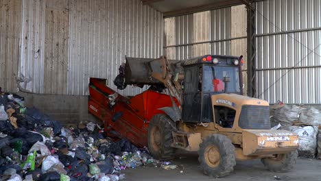 A-bulldozer-dumps-waste-onto-a-conveyor-belt-inside-a-waste-processing-facility