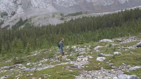 Hiker-walking-up-mountain-buy-forest-followed-Rockies-Kananaskis-Alberta-Canada