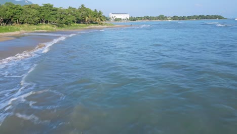 Flying-Over-Splashing-Sea-Waves-At-Playa-Dorada-Beach-In-Puerto-Plata,-Dominican-Republic-In-Summer