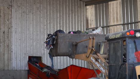 Dumping-waste-onto-a-conveyor-belt-inside-a-waste-processing-facility